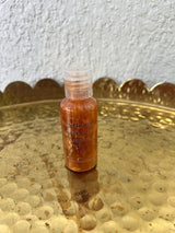 Melanated Beauty Spa Golden Hour Shimmer Body Oil, travel-size bottle on a brass tray