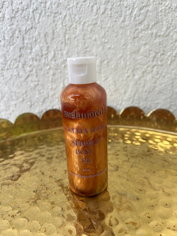 Melanated Beauty Spa Golden Hour Shimmer Body Oil bottle with gold shimmer on a brass tray