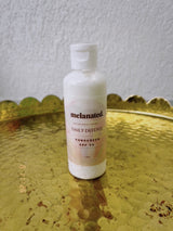 Melanated Beauty Spa Daily Defense SPF 50 Sunscreen bottle on a brass tray
