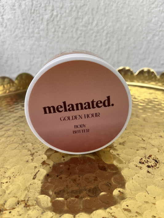 Body butter container labeled 'melanated. GOLDEN HOUR' on a gold tray.