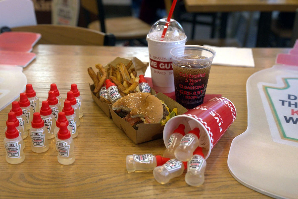 Mini cleanser bottles on the table beside burgers and fries