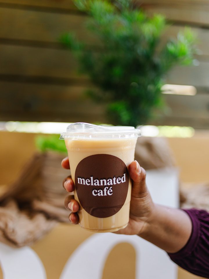 Hand holding a melanated café iced coffee