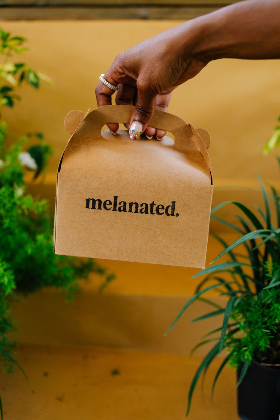 Hand holding a Melanated to-go box