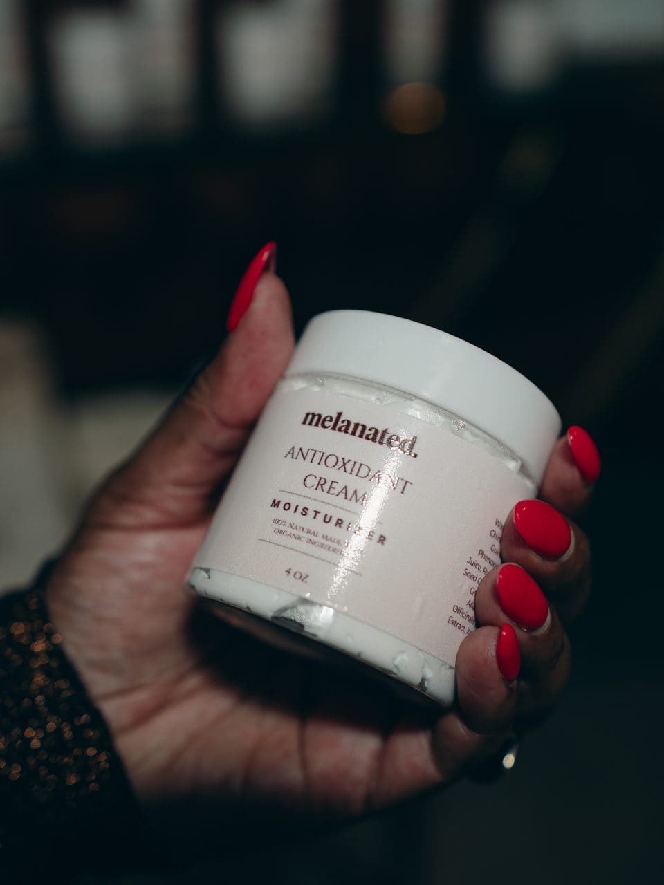 Hand holding a jar of Melanated Antioxidant Cream
